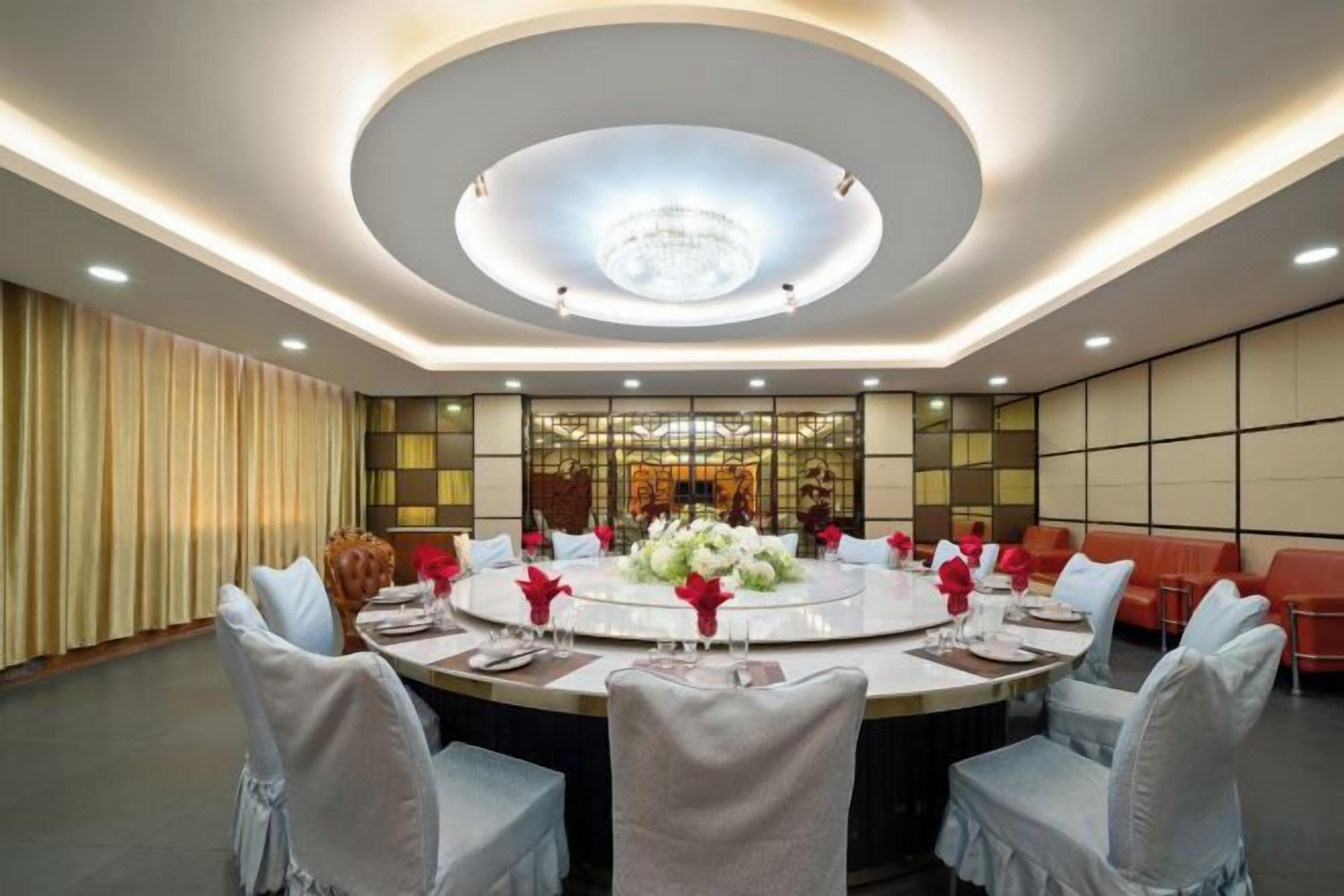 A conference room with a round table, chairs, and a chandelier.