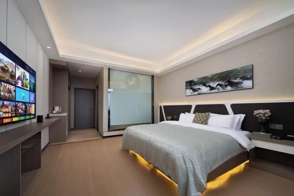Une chambre d’hôtel moderne dotée d’un grand lit, d’un téléviseur à écran plat, d’un tableau et d’une porte coulissante donnant sur un balcon.