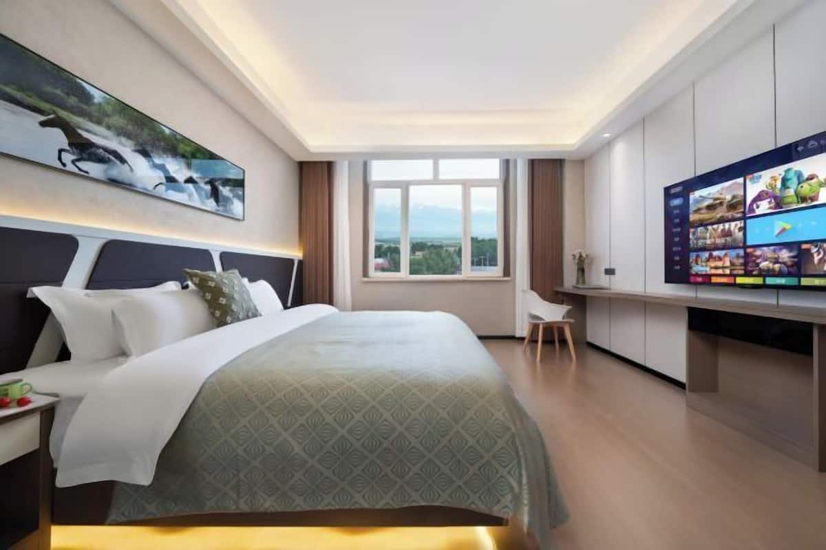 A hotel room with a bed, a desk, a television, and a window with a view.