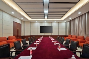 A conference room with a long table, chairs, and a large screen. - Pegasus Hotel (Zhaosu)
