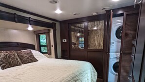 Een slaapkamer met een groot bed, een wasmachine en een deur met uitzicht.