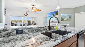 A modern kitchen with a large island, a ceiling fan, and a view of the outdoors. - Island Life! Amazing Balcony-Views-Pool and Patio (Rocky Mount)