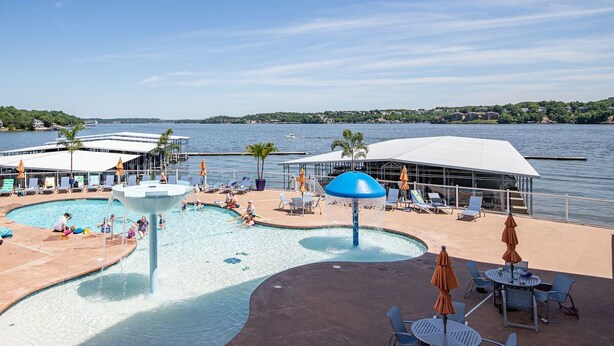 A pool area with lounge chairs and umbrellas, a water feature, and a view of the lake. - Island Life! Amazing Balcony-Views-Pool and Patio (Rocky Mount)