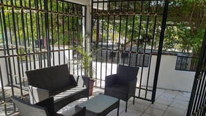 A balcony with a black metal gate, a wicker sofa, two chairs, and a small table. - La Villa Palmier Your quiet House (Puerto Vallarta)
