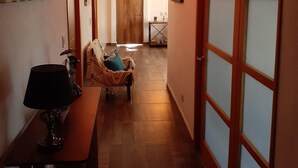 A hallway with a wooden door, a lamp, a chair, and a table. - La Villa Palmier Your quiet House (Puerto Vallarta)