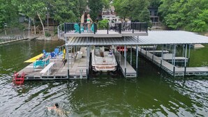 Een steiger met een overdekte zithoek, een boot en een klein gebouw op de achtergrond.