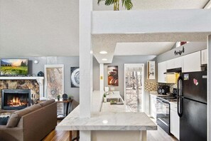 Cozy living and dining space with a stone fireplace, comfortable seating area, and modern kitchen.