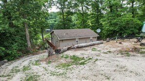 Une maison de plain-pied, dotée d’un toit en pente, entourée d’une forêt dense.