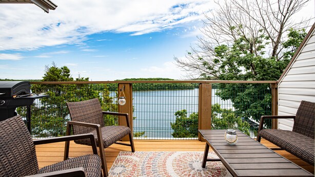 A deck with wicker furniture, a grill, and a view of a lake. - Amazing Views from Balcony, Loft & Gated Pool (Kaiser)
