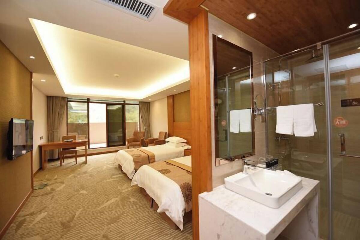 Une chambre d’hôtel dotée d’un grand lit, d’un canapé séparé, d’une douche en verre et d’un téléviseur à écran plat.