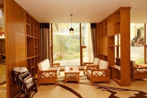 Una habitación con un ventanal grande, muebles de madera y una estantería.