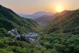 A mountainous landscape with a building featuring multiple floors and a winding road.