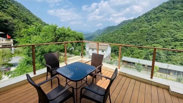 Varanda com mesa e cadeiras, vista para uma paisagem montanhosa.