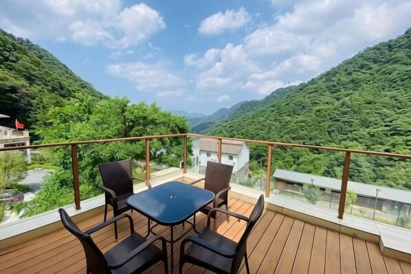 Un balcón con mesa y sillas, con vista a un paisaje montañoso.