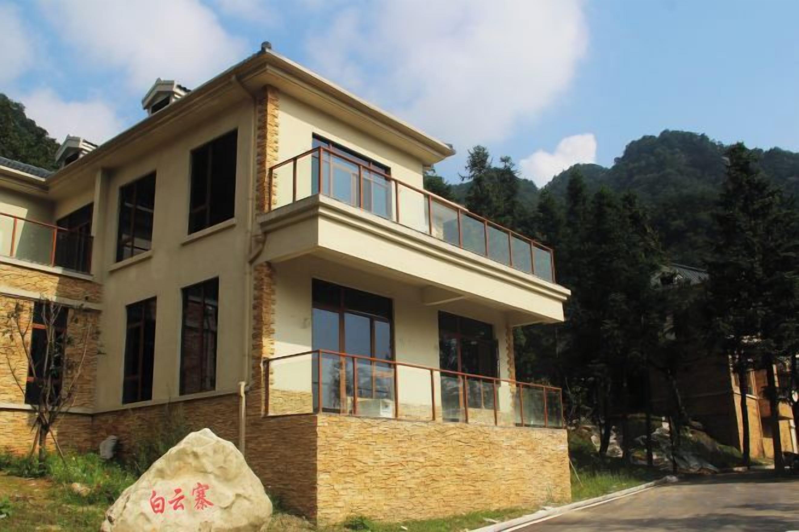 Un edificio de dos pisos con balcón, ventanas amplias y fachada de piedra.