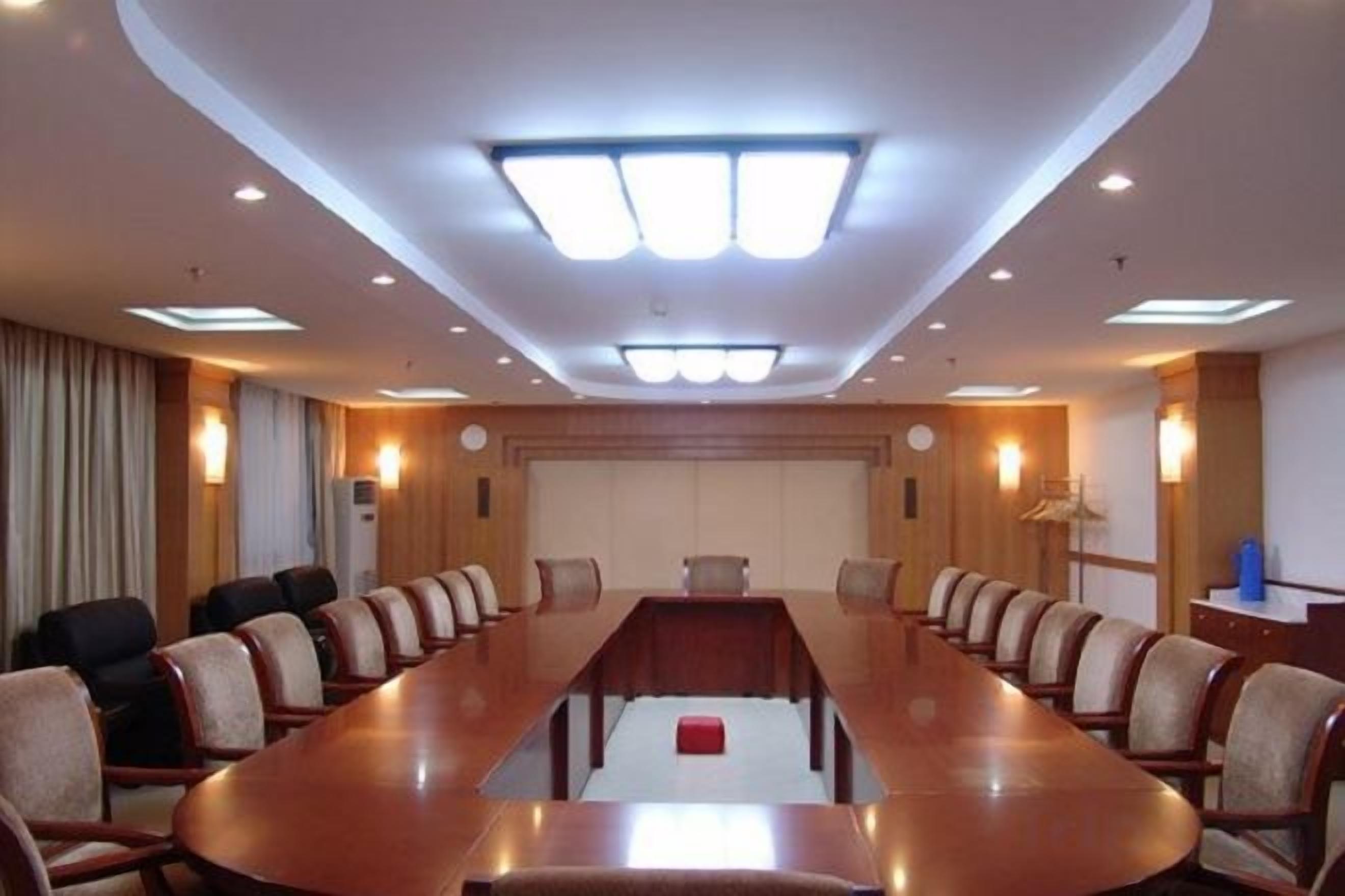 Una sala de conferencias con una mesa larga, sillas y un atril.