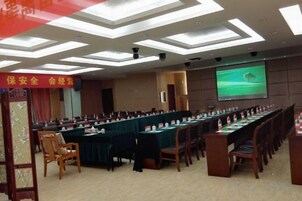 A conference room with a long table, chairs, and a projector screen.