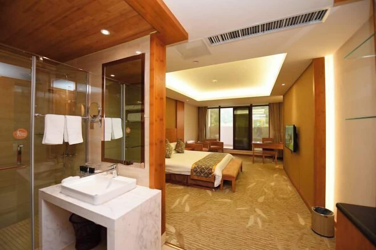 Une chambre d’hôtel dotée d’un grand lit, d’une salle de bain séparée avec une douche en verre et d’un petit coin salon.