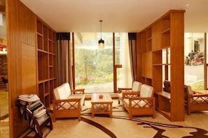 A room with a large window, wooden bookshelves, and a seating area with tables and chairs. - Tiantangzhai Holiday Hotel (Jinzhai)