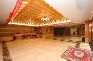 A spacious lobby with a reception desk, a large mirror, and a patterned rug.