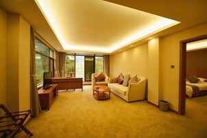 Un hotel moderno con sofá, mesa de centro, televisión y un amplio ventanal con vistas al exterior.