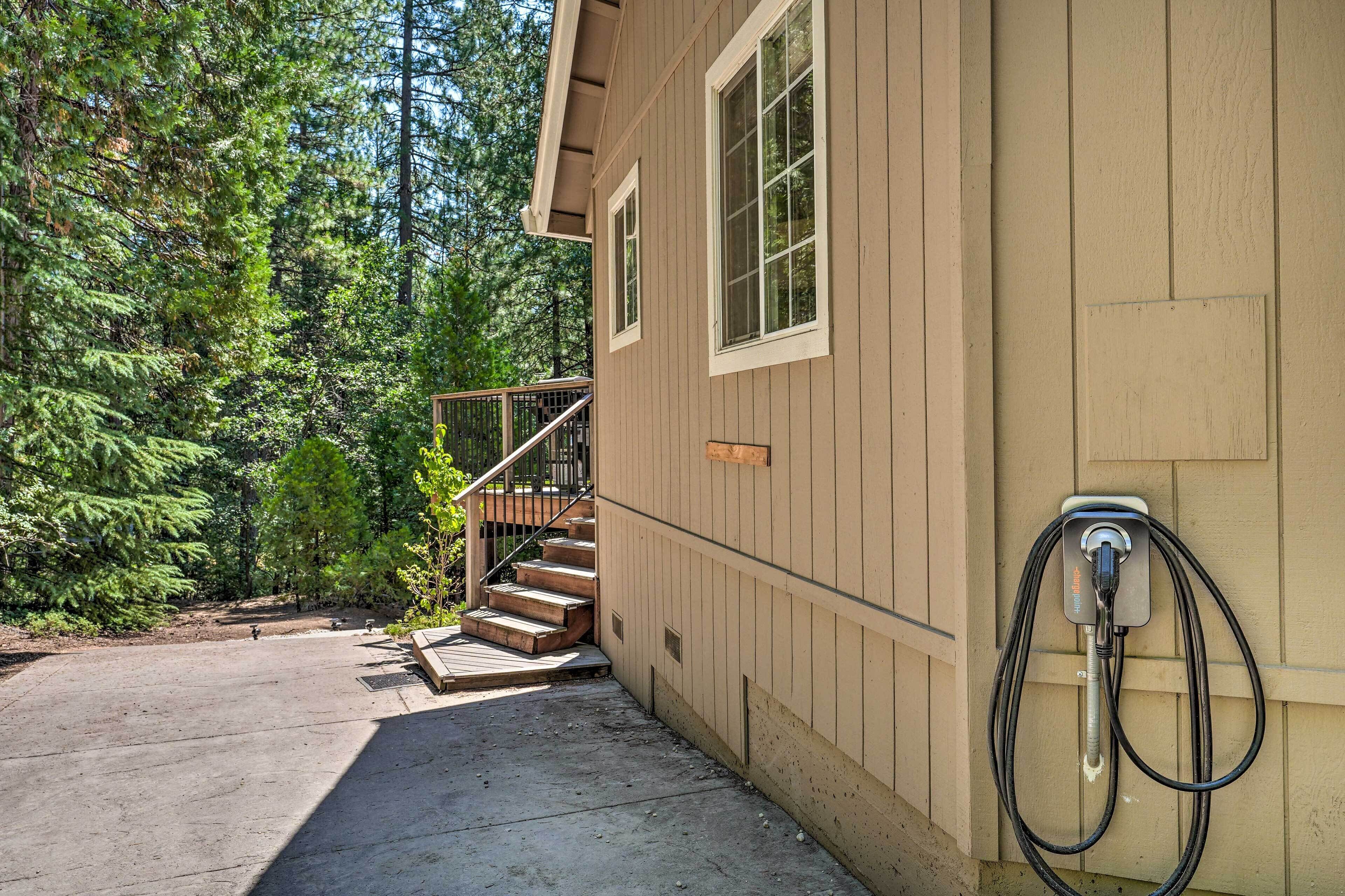 A wooden house with a concrete driveway, a wooden staircase, and a power outlet with a cable.