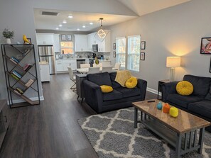 A modern living room with a black sofa, a coffee table, and a bookshelf.