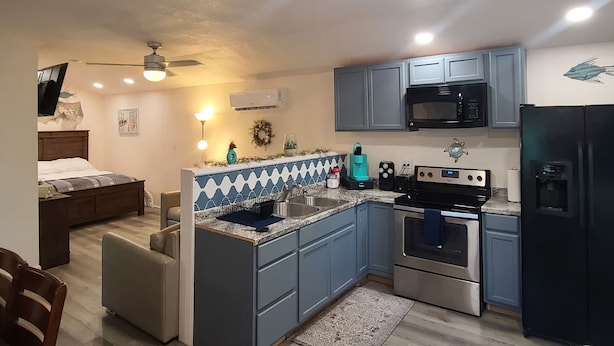 A modern kitchen with blue cabinets, a microwave, a stove, and a refrigerator. - Cute little costal cabin.  One mile from Lake Tenkiller.  Private Spa/Hot Tub  (Cookson)