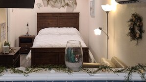 A bedroom with a bed, bedside tables, a wall-mounted air conditioner, and a ceiling fan. - Cute little costal cabin.  One mile from Lake Tenkiller.  Private Spa/Hot Tub  (Cookson)
