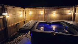 A hot tub with a wooden fence and string lights. - Cute little costal cabin.  One mile from Lake Tenkiller.  Private Spa/Hot Tub  (Cookson)