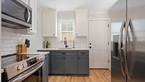 Eine moderne Küche mit weißen Schränken, einem Edelstahl-Kühlschrank, einer Mikrowelle und einem eingebauten Backofen.