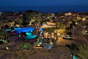 Un resort con varias piscinas, palmeras y vistas al océano.