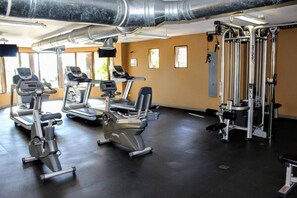 Un gimnasio con cintas de correr, elípticas y equipo de levantamiento de pesas.