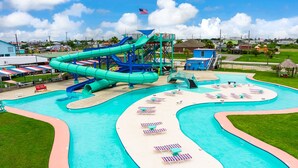 A water park with a large pool, slides, and lounge areas.