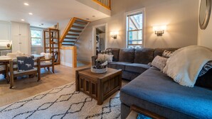 A spacious living room with a blue sofa, wooden coffee table, and a staircase leading to an upper level. - Cozy mountain hideaway for hikers, skiers and chefs! (Truckee)