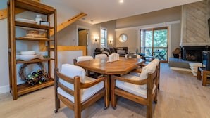 A spacious living room with a wooden dining table and chairs, a built-in bookshelf, and a fireplace. - Cozy mountain hideaway for hikers, skiers and chefs! (Truckee)
