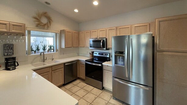 A modern kitchen with stainless steel appliances, wooden cabinets, and a white countertop. - Comfortable Desert Get-Away  (Yuma)