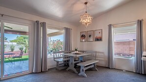 A dining area with a table and benches, large windows with curtains, and a hanging light fixture. - Comfortable Desert Get-Away  (Yuma)