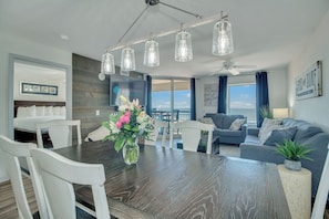 Una sala de estar moderna con comedor, ventanas amplias y vistas al exterior.