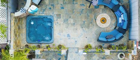 A rooftop patio with a hot tub, curved blue seating, and potted plants.