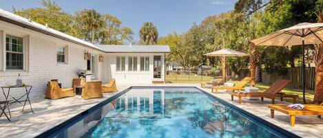 A swimming pool with lounge chairs and a patio area.
