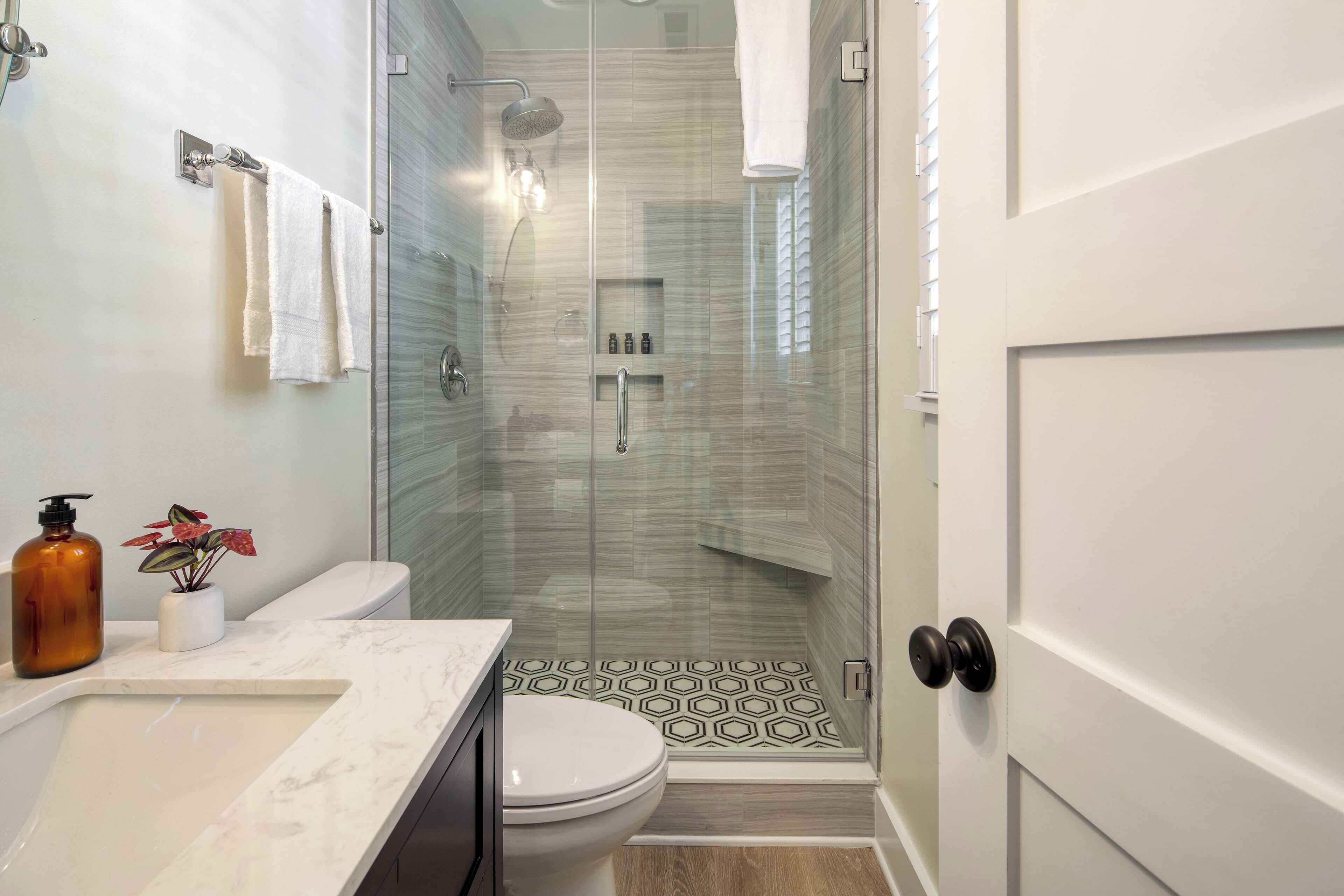 Un baño moderno con cabina de ducha de vidrio, lavabo de mármol y un inodoro.
