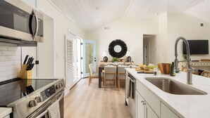 A modern kitchen with a built-in oven, microwave, and stainless steel sink. - Sawyer by Avantstay Stunning Isle Of Palms Home w/ Pool! (Isle of Palms)