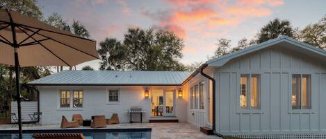 A house with a swimming pool, outdoor furniture, and a covered patio area.