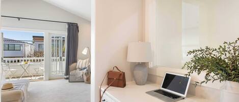 A modern room with a laptop on a desk, a potted plant, and a view of the outside balcony.