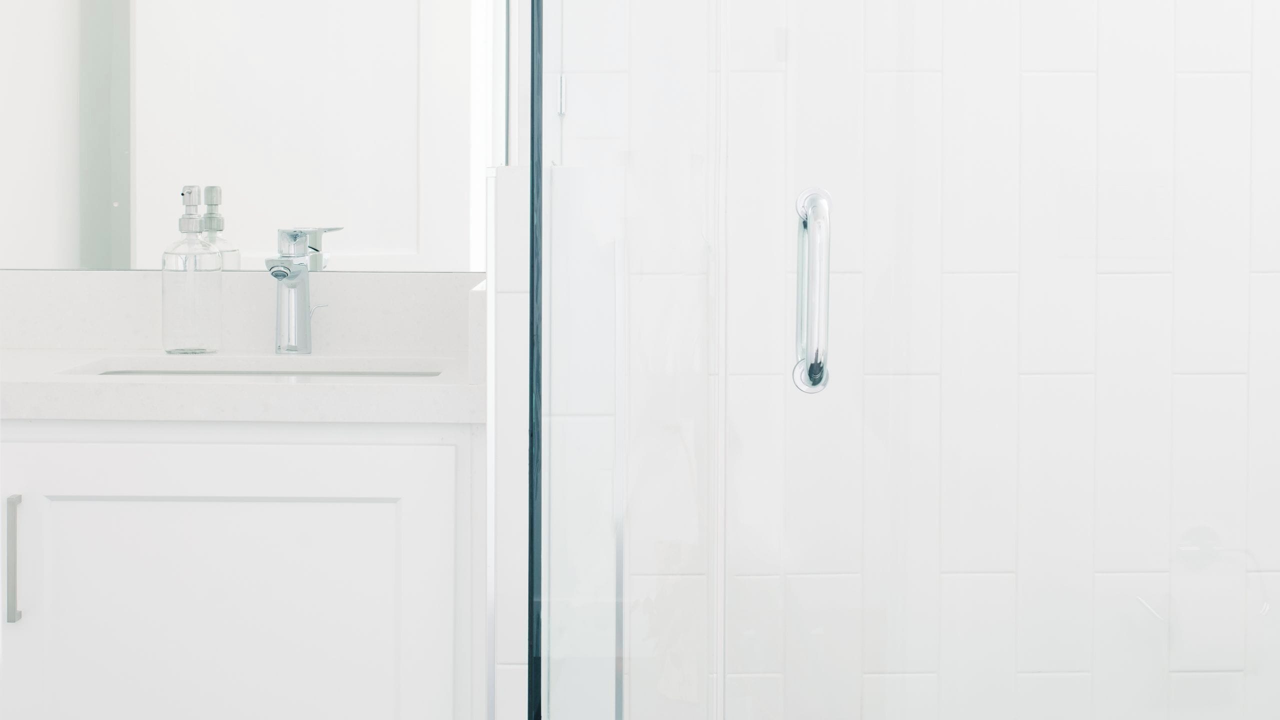 A bathroom with a glass shower enclosure, a white sink with a faucet, and a mirror above the sink.
