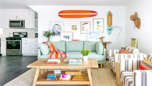 A modern living room with a sofa, coffee table, and books. - O'neill I by Avantstay Coastal Paradise Steps From Beach Modern Decor (Newport Beach)