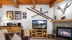 A cozy living room with a fireplace, a television, and ski-themed decorations. - Riverside Condos B101 by Avantstay Condo Close To Downtown, Town Park & Ski Lift #8 (Telluride)