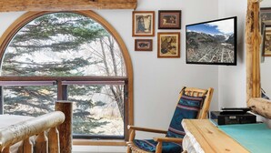 A cozy room with a large arched window, wooden furniture, and framed pictures on the wall. - Riverside Condos B101 by Avantstay Condo Close To Downtown, Town Park & Ski Lift #8 (Telluride)