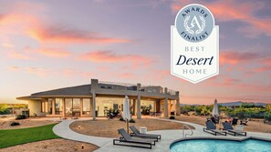 A desert home with a pool, lounge chairs, and a patio area.